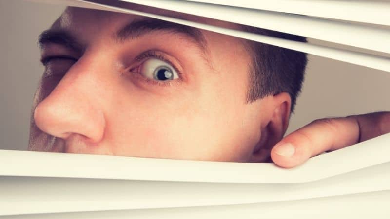 Man looking through blinds